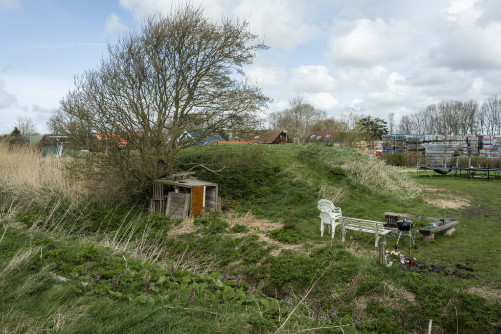 Rustieke houten barbecuehut met gekleurde campingstoelen in Schoorldam, Noord-Holland - Poster op A2 door Niek de Greef